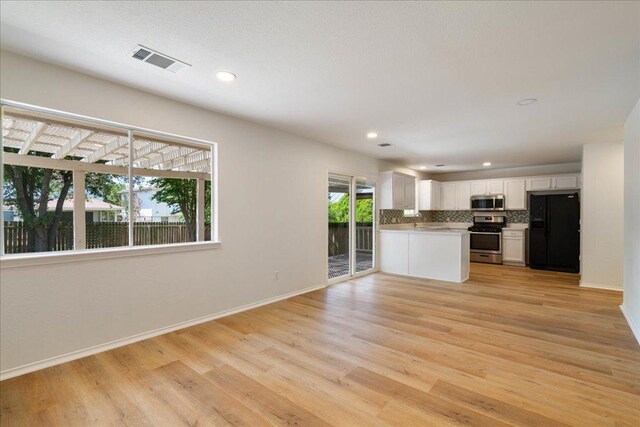 1025 Doras Dr, Pflugerville, TX 78660 - kitchen featuring stainless steel appliances, backsplash, open floor plan, light wood-style flooring, and light countertops