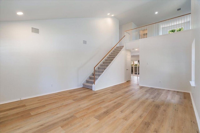 1025 Doras Dr, Pflugerville, TX 78660 - unfurnished living room featuring stairs, healthy amount of natural light, wood finished floors, recessed lighting, and a towering ceiling