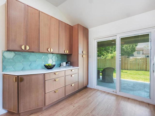 2401 Lendall Ln, Austin, TX 78744 - kitchen featuring light countertops, decorative backsplash, light wood-style floors, and lofted ceiling