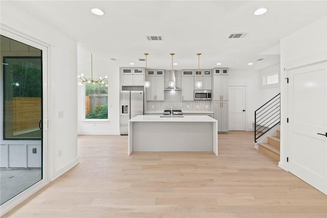 3321 Hemlock Ave Unit 2, Austin, TX 78722 - kitchen with appliances with stainless steel finishes, decorative backsplash, wall chimney range hood, an island with sink, and light countertops