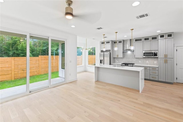 3321 Hemlock Ave Unit 2, Austin, TX 78722 - kitchen featuring stainless steel appliances, wall chimney exhaust hood, gray cabinetry, ceiling fan, and light wood-style floors