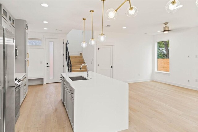 3321 Hemlock Ave Unit 2, Austin, TX 78722 - kitchen with gray cabinets, light wood-style floors, an island with sink, glass insert cabinets, and appliances with stainless steel finishes
