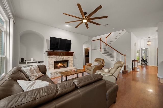 13129 Halsell Dr, Austin, TX 78732 - living area featuring a ceiling fan, stairway, a fireplace, wood finished floors, and arched walkways