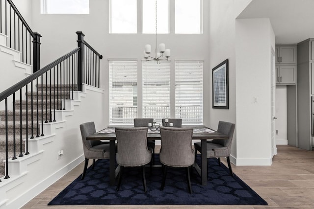 904 Arundel Rd, Lakeway, TX 78738 - dining space featuring stairway, a chandelier, a towering ceiling, baseboards, and light wood finished floors
