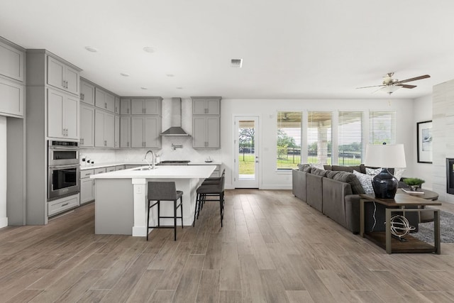 904 Arundel Rd, Lakeway, TX 78738 - kitchen featuring wall chimney exhaust hood, stainless steel appliances, gray cabinets, and wood finished floors