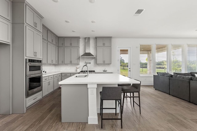 904 Arundel Rd, Lakeway, TX 78738 - kitchen with gray cabinetry, wall chimney exhaust hood, stainless steel double oven, a sink, and light countertops