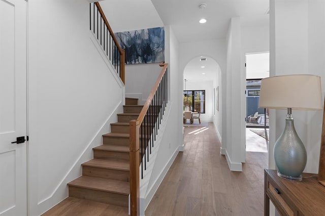 1207 Aggie Ln, Austin, TX 78757 - stairs featuring arched walkways, wood finished floors, and recessed lighting