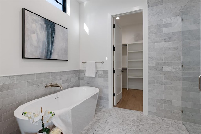 1207 Aggie Ln, Austin, TX 78757 - bathroom with tile walls, a freestanding bath, a walk in closet, and wainscoting