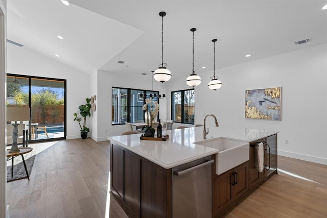 1207 Aggie Ln, Austin, TX 78757 - kitchen featuring stainless steel dishwasher, light countertops, light wood-style floors, pendant lighting, and recessed lighting