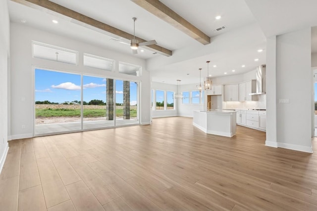 3236 Honeywood Dr, Leander, TX 78641 - unfurnished living room featuring light wood finished floors, beam ceiling, ceiling fan, a chandelier, and recessed lighting