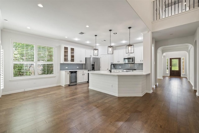 14408 Broadwinged Hawk Dr, Austin, TX 78738 - kitchen featuring stainless steel appliances, arched walkways, beverage cooler, light countertops, and white cabinetry