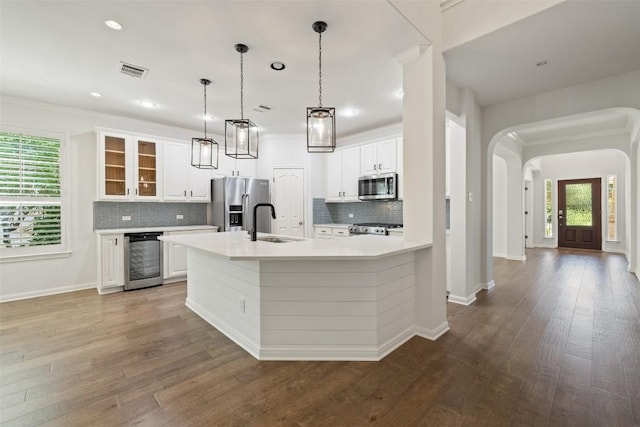 14408 Broadwinged Hawk Dr, Austin, TX 78738 - kitchen featuring appliances with stainless steel finishes, a sink, wine cooler, arched walkways, and decorative backsplash