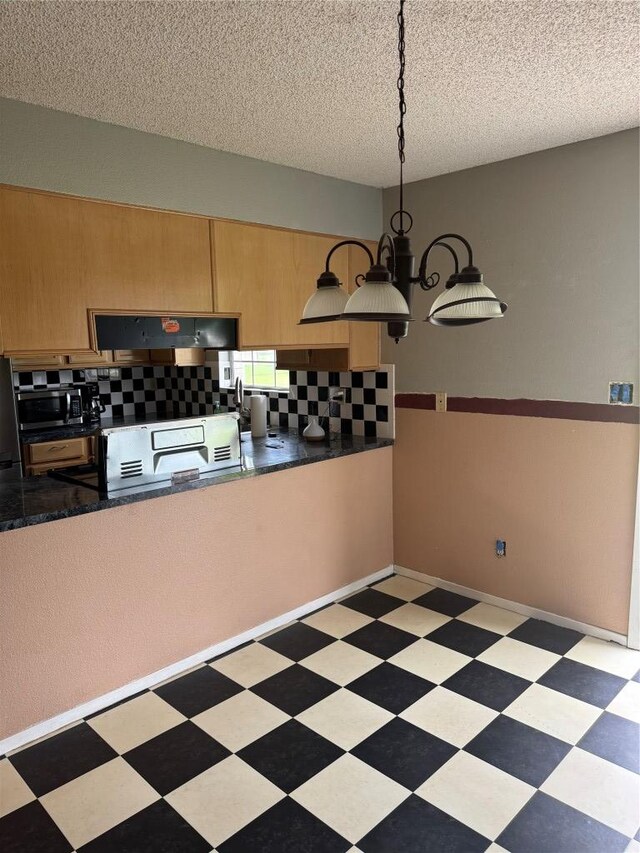 405 Lynch St, Smithville, TX 78957 - kitchen with ventilation hood, tile patterned floors, stainless steel microwave, a textured ceiling, and dark countertops