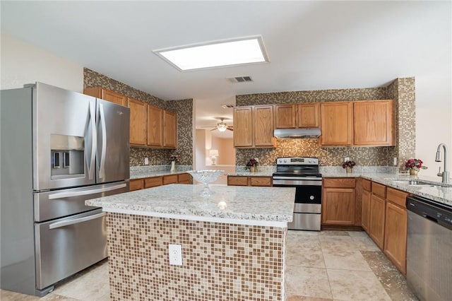 11228 Pickard Ln, Austin, TX 78748 - kitchen with stainless steel appliances, a sink, under cabinet range hood, tasteful backsplash, and light stone counters