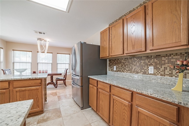 11228 Pickard Ln, Austin, TX 78748 - kitchen with freestanding refrigerator, tasteful backsplash, brown cabinets, and light stone countertops