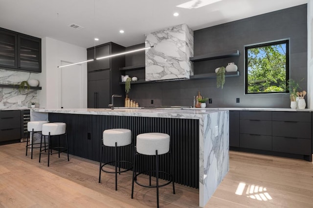 2106 Thornton Rd, Austin, TX 78704 - kitchen featuring open shelves, modern cabinets, a large island with sink, light wood finished floors, and tasteful backsplash
