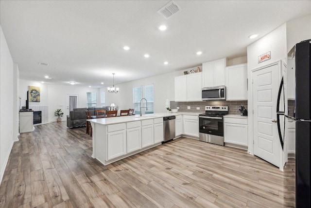7008 Daniel Ranch Dr, Austin, TX 78744 - kitchen with stainless steel appliances, a sink, a peninsula, open floor plan, and light wood-type flooring