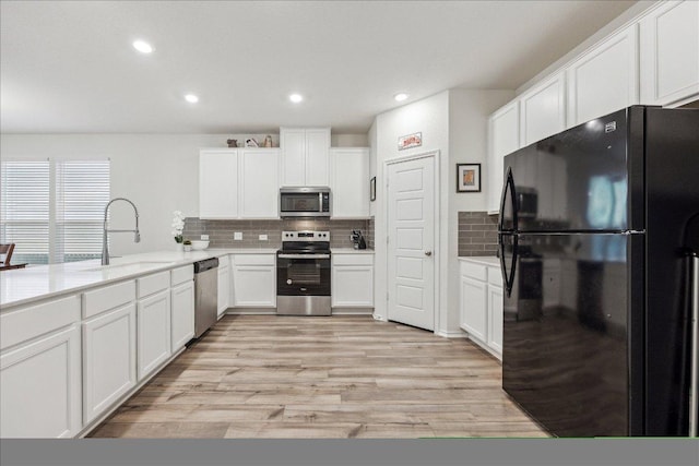 7008 Daniel Ranch Dr, Austin, TX 78744 - kitchen featuring stainless steel appliances, backsplash, white cabinetry, light wood-style floors, and recessed lighting