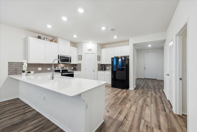 7008 Daniel Ranch Dr, Austin, TX 78744 - kitchen with stainless steel appliances, a peninsula, wood finished floors, light countertops, and recessed lighting