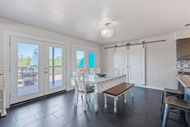 156 Lakefront Dr, Point Venture, TX 78645 - dining space with french doors, a barn door, a textured ceiling, baseboards, and a chandelier