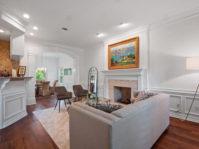 1300 Puddleby Cv, Austin, TX 78746 - living room featuring arched walkways, a decorative wall, ornamental molding, dark wood-style flooring, and a tiled fireplace
