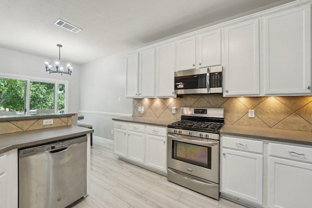 504 Chaparral Dr, Leander, TX 78641 - kitchen featuring stainless steel appliances, a chandelier, white cabinetry, and dark countertops