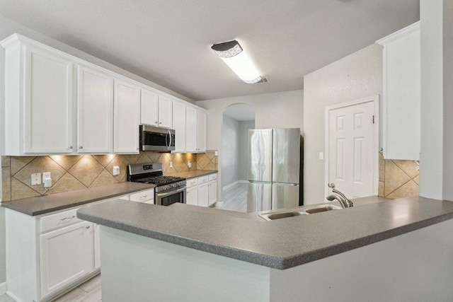 504 Chaparral Dr, Leander, TX 78641 - kitchen featuring stainless steel appliances, arched walkways, a sink, and white cabinetry