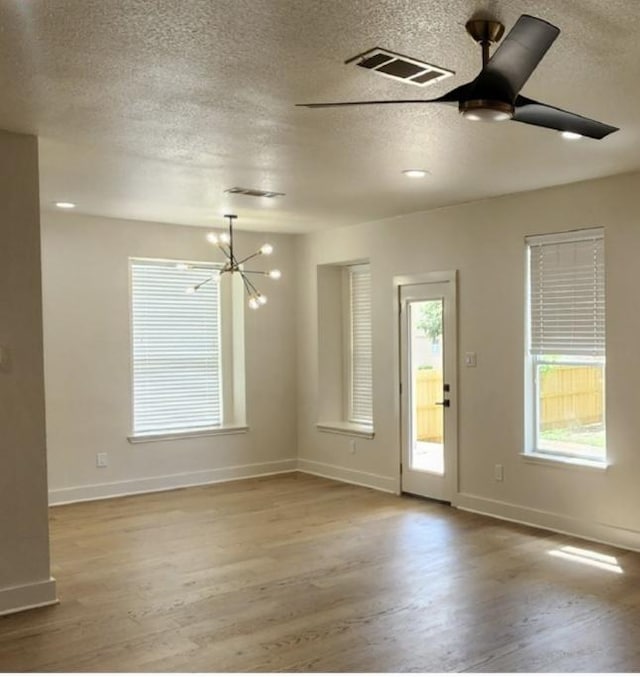 117 Waterloo Dr, Kyle, TX 78640 - spare room featuring a textured ceiling, wood finished floors, a chandelier, and a ceiling fan