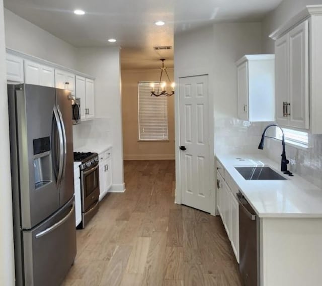 117 Waterloo Dr, Kyle, TX 78640 - kitchen with appliances with stainless steel finishes, a chandelier, white cabinets, backsplash, and recessed lighting