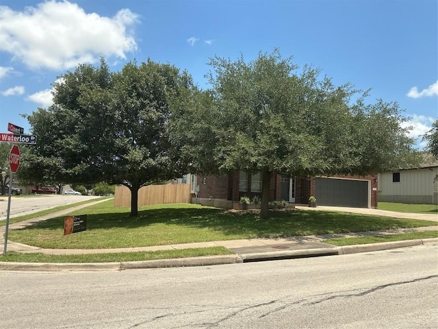 117 Waterloo Dr, Kyle, TX 78640 - view of property hidden behind natural elements featuring an attached garage, concrete driveway, and brick siding