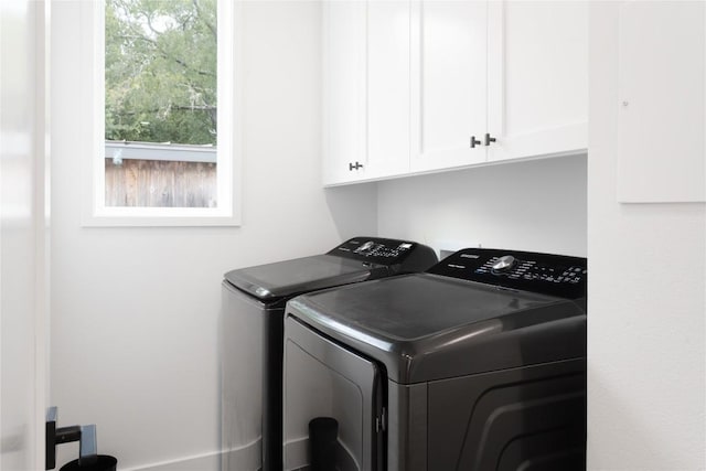laundry area with separate washer and dryer and cabinet space