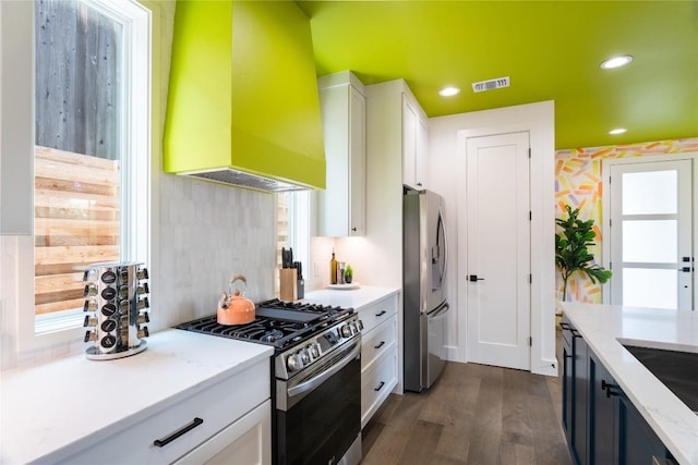 kitchen featuring appliances with stainless steel finishes, custom range hood, white cabinetry, dark wood-style flooring, and recessed lighting