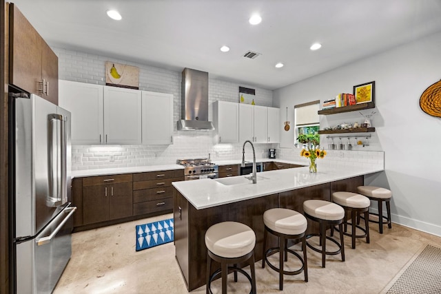 2100 E 10th St, Austin, TX 78702 - kitchen with stainless steel appliances, wall chimney exhaust hood, a sink, a breakfast bar, and light countertops