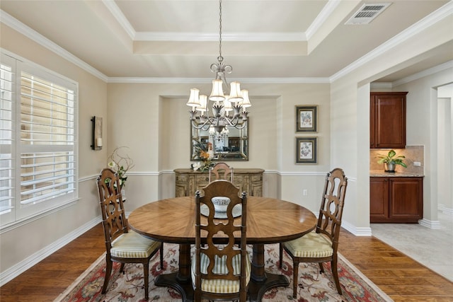 218 Duck Creek Ln, Georgetown, TX 78633 - dining space with light wood finished floors, a tray ceiling, a chandelier, ornamental molding, and baseboards