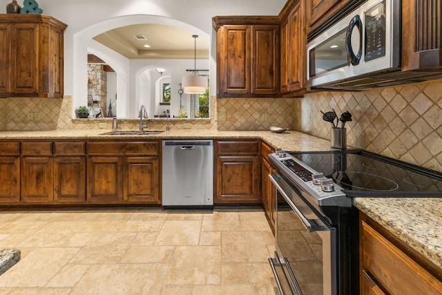 2804 Lohmans Ford Rd Unit B, Lago Vista, TX 78645 - kitchen featuring appliances with stainless steel finishes, backsplash, stone tile flooring, light stone counters, and arched walkways