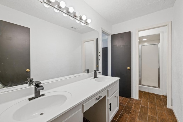 1008 Woodshadows Dr, Harker Heights, TX 76548 - bathroom with wood finish floors, double vanity, a shower stall, and a textured ceiling