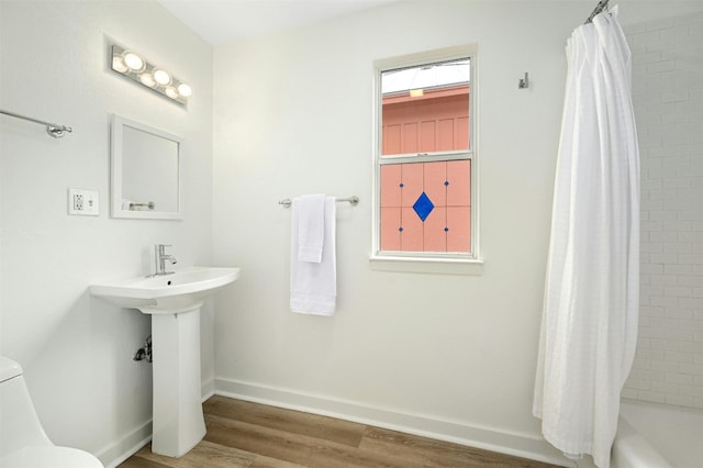 1112 W 10th St, Austin, TX 78703 - full bath featuring wood finished floors, toilet, shower / tub combo with curtain, and baseboards