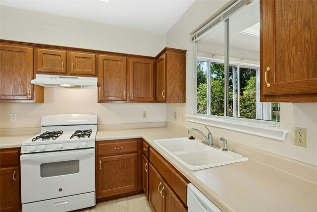112 Anemone Way, Georgetown, TX 78633 - kitchen with white gas range, under cabinet range hood, a sink, and brown cabinetry