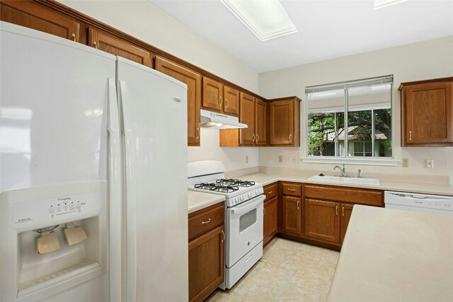 112 Anemone Way, Georgetown, TX 78633 - kitchen featuring white appliances, under cabinet range hood, a sink, light countertops, and brown cabinets