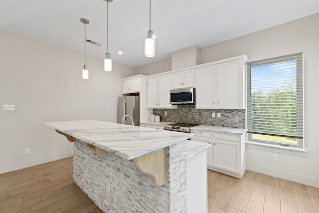 757 Canyon Bnd, Canyon Lake, TX 78133 - kitchen with stainless steel appliances, tasteful backsplash, a kitchen island with sink, light wood finished floors, and white cabinets