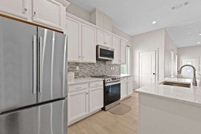 757 Canyon Bnd, Canyon Lake, TX 78133 - kitchen with appliances with stainless steel finishes, tasteful backsplash, light wood-style flooring, white cabinets, and recessed lighting