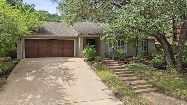 1302 Wilderness Dr, Austin, TX 78746 - view of front of house with brick siding, a garage, concrete driveway, and roof with shingles