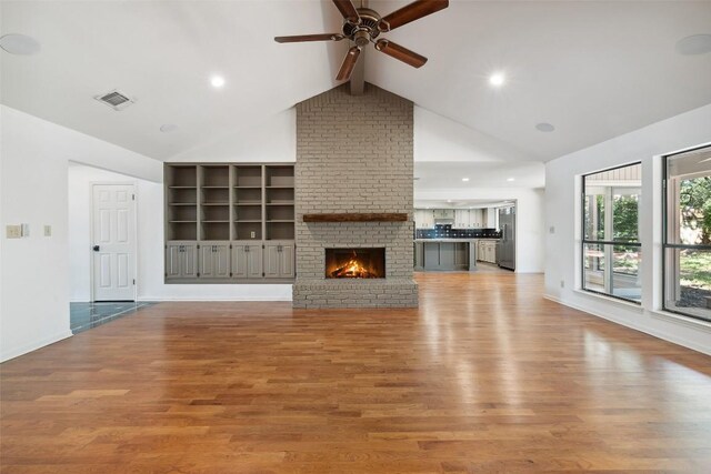 1302 Wilderness Dr, Austin, TX 78746 - unfurnished living room featuring ceiling fan, beamed ceiling, light wood finished floors, a brick fireplace, and high vaulted ceiling