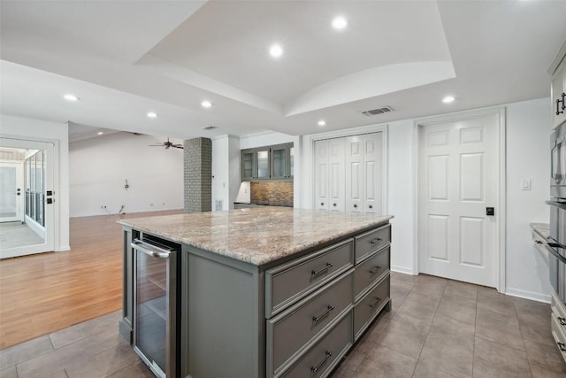 1302 Wilderness Dr, Austin, TX 78746 - kitchen featuring wine cooler, gray cabinetry, recessed lighting, a center island, and tasteful backsplash