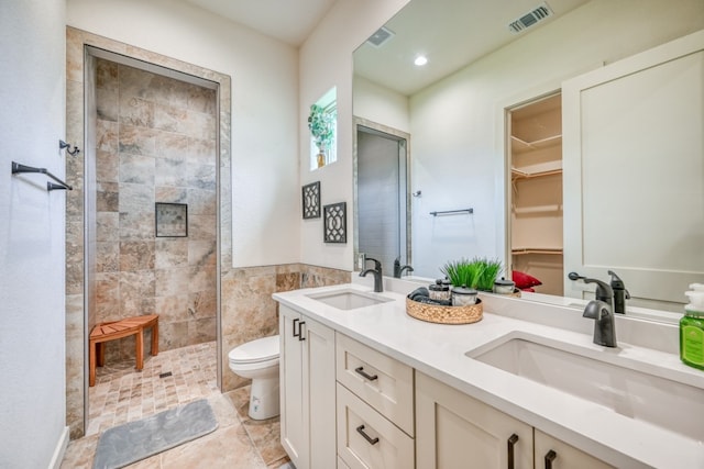 302 Parallel Cir, Horseshoe Bay, TX 78657 - bathroom with double vanity, toilet, a tile shower, a walk in closet, and recessed lighting