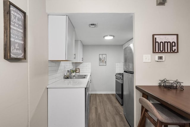 1800 Lavaca St Unit 307, Austin, TX 78701 - kitchen featuring appliances with stainless steel finishes, wood finished floors, white cabinets, backsplash, and light countertops