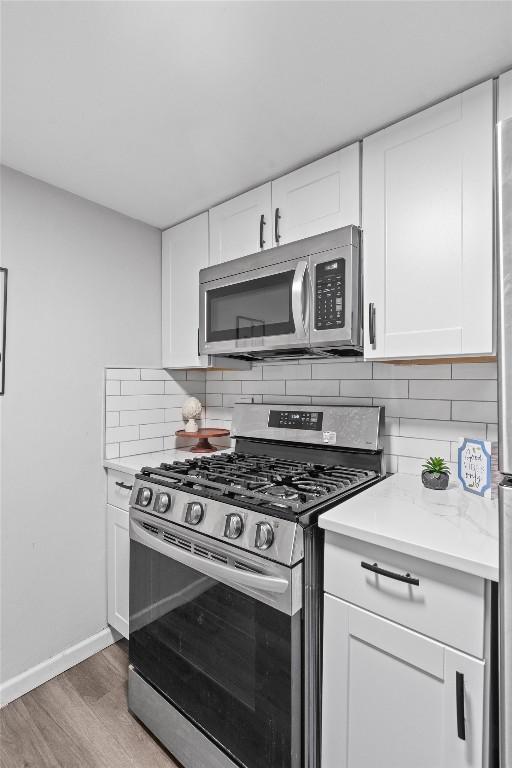 1800 Lavaca St Unit 307, Austin, TX 78701 - kitchen featuring stainless steel appliances, light wood-style floors, backsplash, and white cabinetry