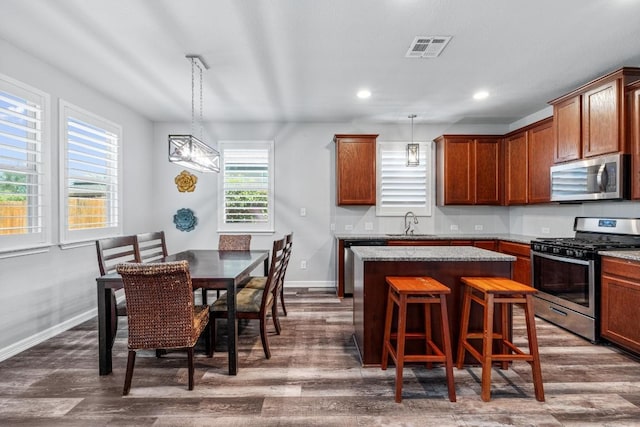 529 Cinnamon Teal Ln, Leander, TX 78641 - kitchen with appliances with stainless steel finishes, a sink, a kitchen island, dark wood-style flooring, and recessed lighting