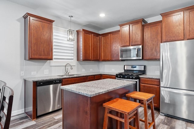 529 Cinnamon Teal Ln, Leander, TX 78641 - kitchen featuring appliances with stainless steel finishes, a sink, wood finished floors, a center island, and recessed lighting