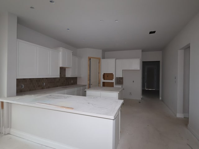 100 White Magnolia Cv, Georgetown, TX 78628 - kitchen featuring a peninsula, tasteful backsplash, white cabinets, baseboards, and concrete flooring